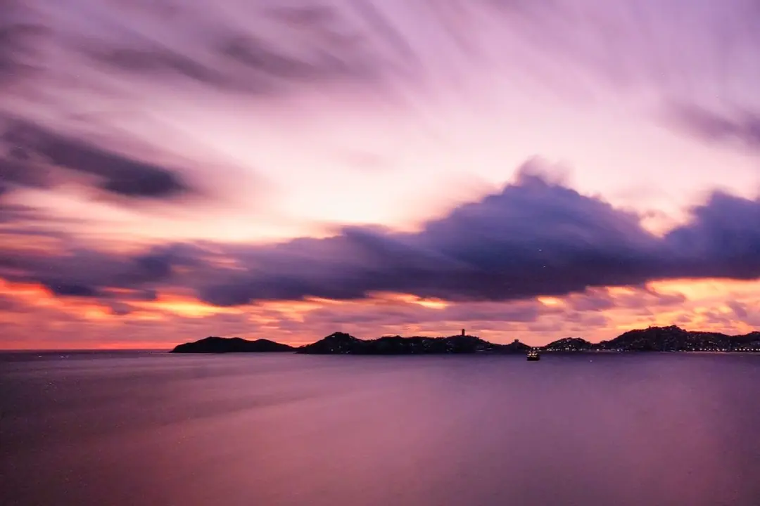 Cielo morado y rosa sobre el mar al atardecer, fotografiado con larga exposición