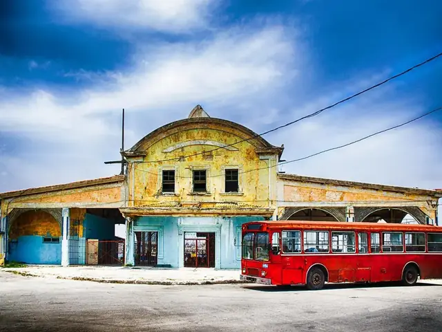 Autobús rojo estacionado frente a un edificio amarillo antiguo