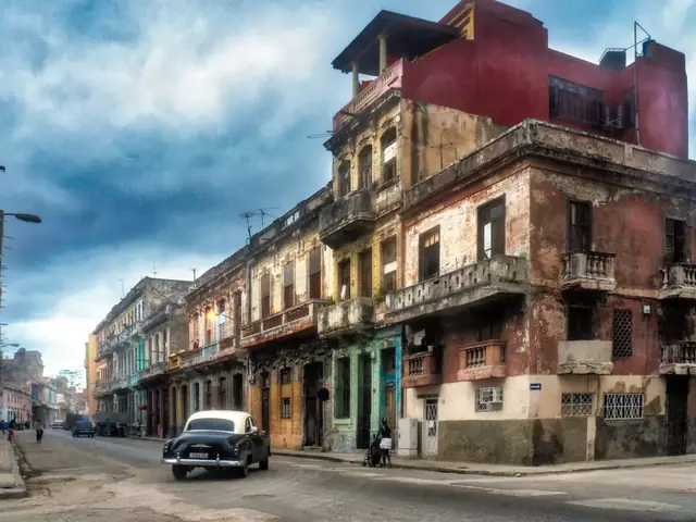 Calle de La Habana con edificios desgastados, un auto clásico y un cielo con nubes dramáticas