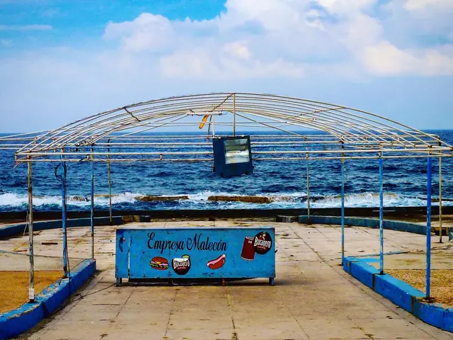 Quiosco azul bajo una estructura metálica frente al mar, en Cuba